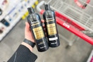 person holding 2 bottles of tresemme shampoo over a cvs cart