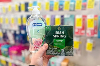 person holding a bottle of softsoap hand soap and a pack of irish spring bar soap