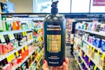 person holding a bottle of tresemme shampoo in an aisle