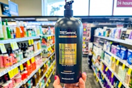 person holding a bottle of tresemme shampoo in an aisle