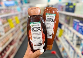 hand holding two bottles of Garnier Whole Blends