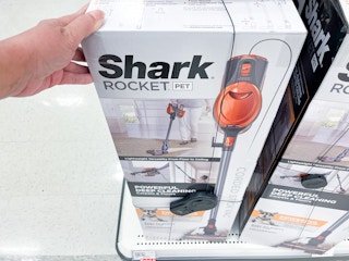 hand grabbing a shark rocket vacuum sitting on a target shelf