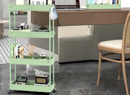 a green storage cart in a room with items next to a desk