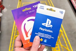 hand holding playstation and taco bell gift cards