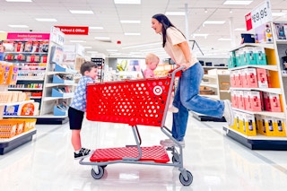 a woman riding a target shopping cart with her kids
