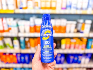 person holding a bottle of coppertone sunscreen