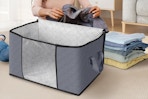 a person folding clothes into a storage bag