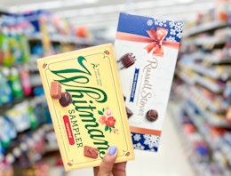 hand holding one box of Russell Stover and Whitman chocolates