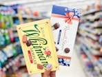 hand holding one box of Russell Stover and Whitman chocolates