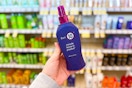 person holding a bottle of it's a 10 miracle leave-in product in front of shelves