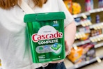 person holding a tub of cascade dishwasher pods