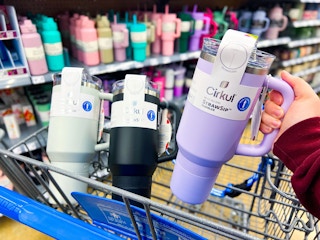 hand holding a purple 40-ounce Cirkul tumbler in front of a black and sage tumblers