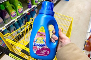 hand holding snuggle fabric softener above dollar general shopping cart