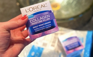 A hand holding a box of L'Oreal collagen cream above an Amazon delivery envelope