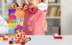 a talking giraffe on a table in front of a little girl