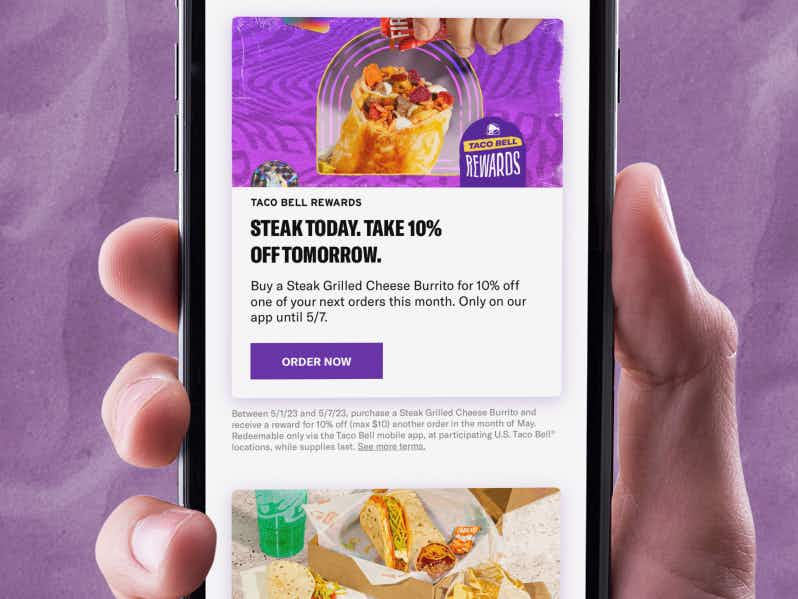 person holding phone with screenshot of taco bell cinco de mayo rewards deal