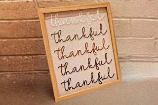 Lifestyle image of the 8x10 Way to Celebrate Thankful decor with brick wall in the background