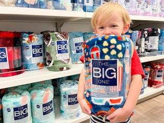 A kid holding a The Big One plush throw in an aisle at Kohl's