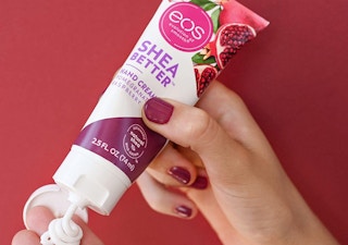 hands using a tube of eos pomegranate raspberry hand cream