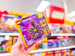 hand holding a spider lego set in front of toy signage at target