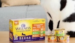 a box of canned cat food next to a cat