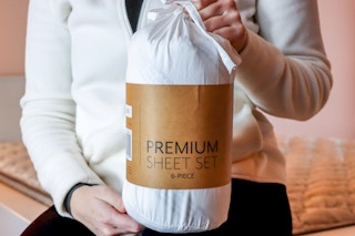 a person holding up a linens and hutch sheet set 