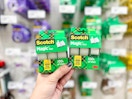 a hand holding boxes of Scotch tape rolls