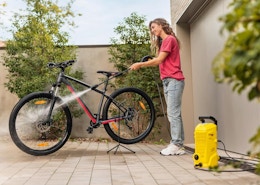 a person pressure washing a bike outside