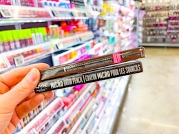 hand holding two nyx eyebrow pencils in walmart aisle