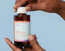 a hand holding a bottle of face toner