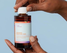 a hand holding a bottle of face toner