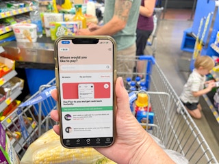 cellphone being held displaying the Fluz app in front of grocery store checkout
