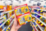 person holding 2 boxes of barnums animal crackers in an aisle