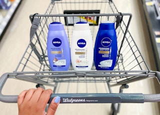 hand pushing shopping cart with three bottles of Nivea body washes