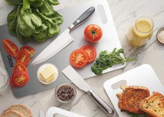 a titanium cutting board with food and knives on top