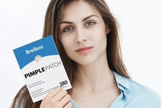a woman holding pimple patches