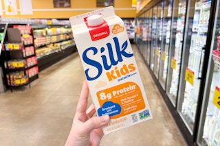hand holding a carton of silk kids oat milk