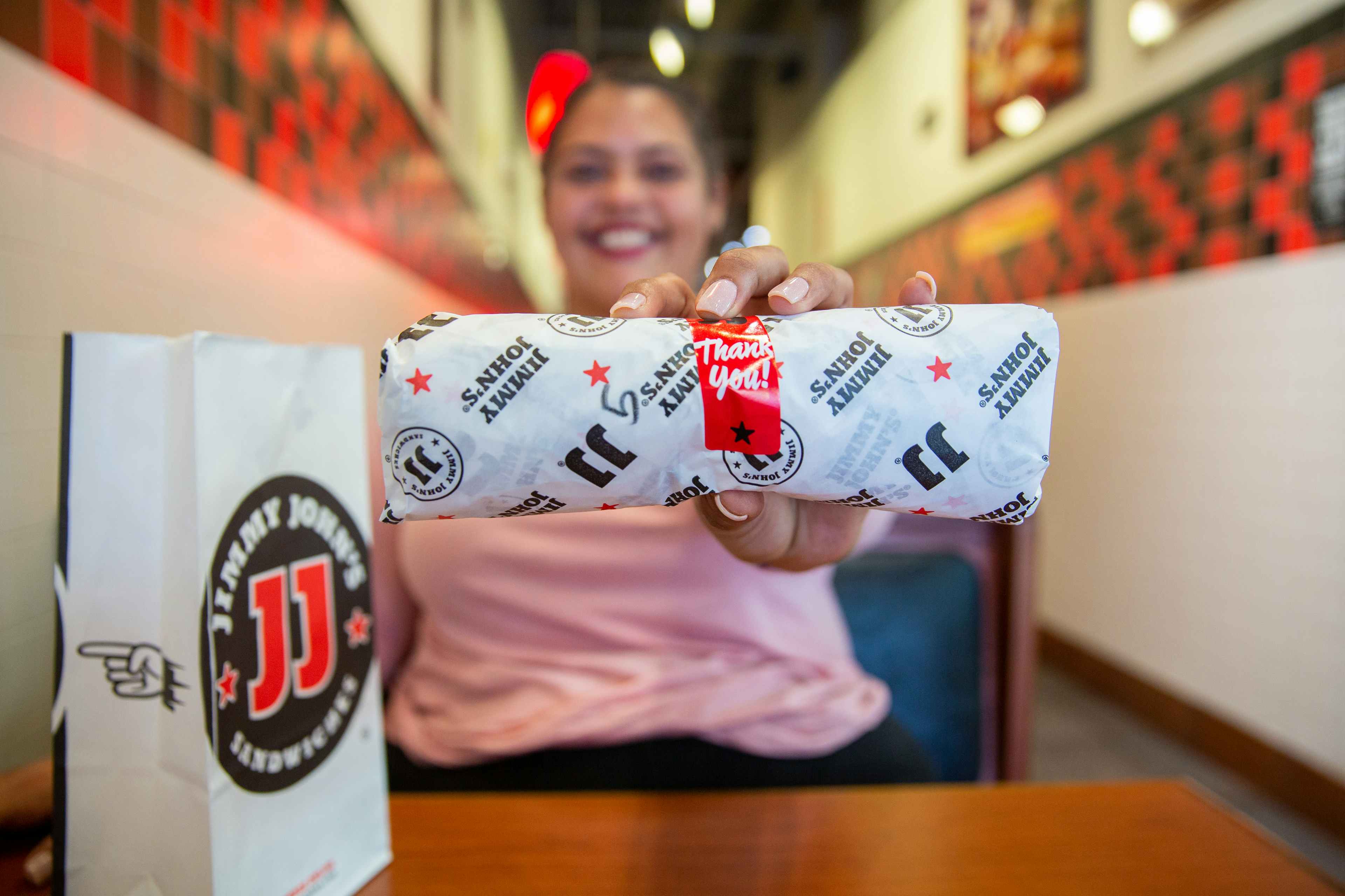a person holding out a jimmy john sandwich 