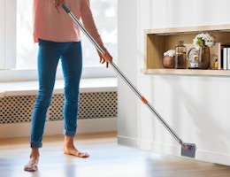 a person cleaning the baseboards with a mop