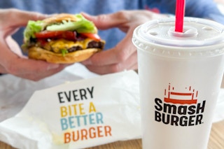 a person holding a burger at smash burger