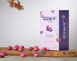 A box of pink prenatal gum vitamins on a wood block.