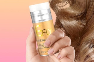 a hand holding a hair wax stick near blonde curls