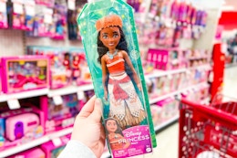 hand holding a Moana Disney fashion doll in the toy aisle