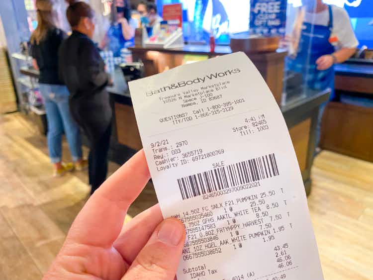 Hand holding Bath & Body Works receipt in store with checkout counter in the background
