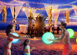 a family playing with glowing beach balls on a beach