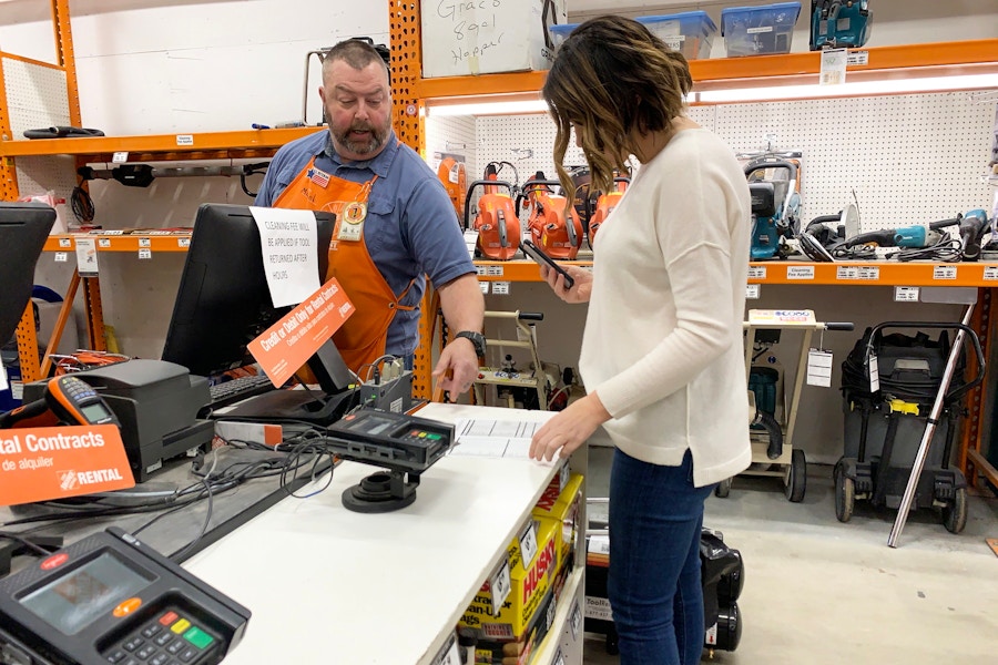 A woman talking to an employee in the tool rental shop at The Home Depot.