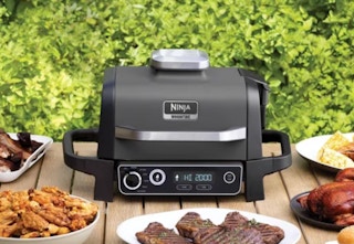 the Ninja Master Grill/Smoker on a table surrounded by food