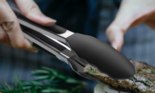 cooking tongs holding meat