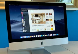 An Apple iMac on a desk with a website displayed on the screen.