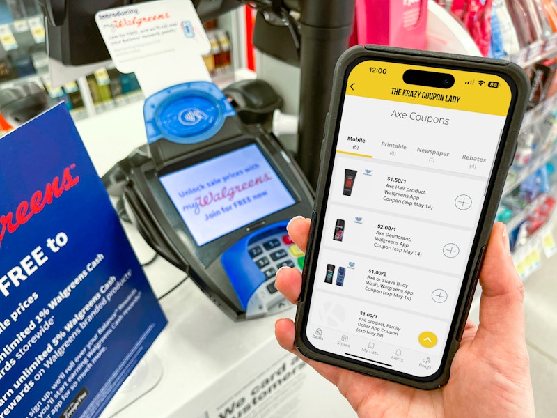 Someone holding up a phone showing Axe coupons on the KCL app in front of a Walgreens counter